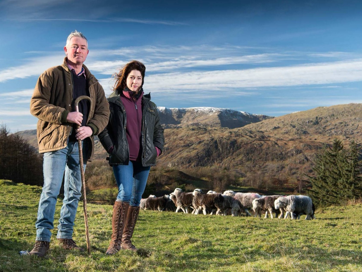 Jon and Jo of Yew Tree Farm standing on the fell with their Herdwick flock